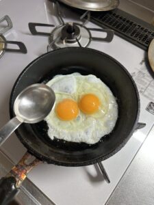 卵を入れたフライパンに水を入れる